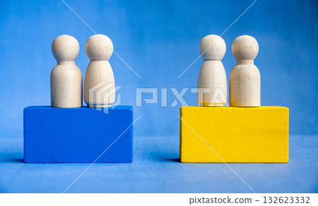Four wooden pegs on a yellow and blue blocks symbolizing inclusion and leadership. 132623332