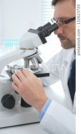 Medical scientist wearing gloves using microscope analyzing samples in modern laboratory doing scientific research. Medicine, healthcare and science concept Medical scientist wearing gloves using microscope analyzing samples in modern laboratory doing scientific research. Medicine, healthcare and science concept 132623720