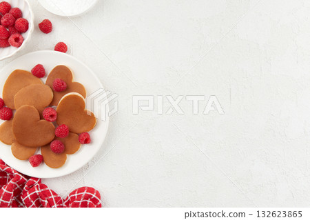 A heap of heart shaped pancakes on the white plate with raspberries on the white background A heap of heart shaped pancakes on the white plate with raspberries on the white background 132623865
