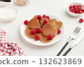 A heap of heart shaped pancakes on the white plate with raspberries on the white background 132623869