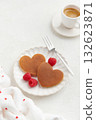 Two heart shaped pancakes with raspberries and a fork on the white plate on white background 132623871