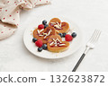 A heap of heart shaped pancakes with berries and a fork on the white plate on grey background 132623872