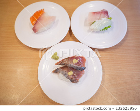 【日本】傳送帶壽司餐廳的餐桌上擺放著一排鮪魚和鮭魚握壽司。 【日本】傳送帶壽司餐廳的餐桌上擺放著一排鮪魚和鮭魚握壽司。 132623950