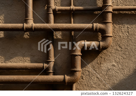 Industrial metal pipes network mounted on textured wall with sunlight casting shadows creating geometric urban patterns, AI Generative 132624327