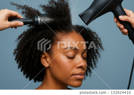 African american woman enjoying professional hair care with styler brush and blow dryer in modern salon against blue background, AI Generative 132624410