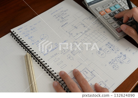 An architect is working on a plan in a grid notebook An architect is working on a plan in a grid notebook 132624890