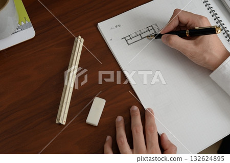 An architect is working on a plan in a grid notebook An architect is working on a plan in a grid notebook 132624895