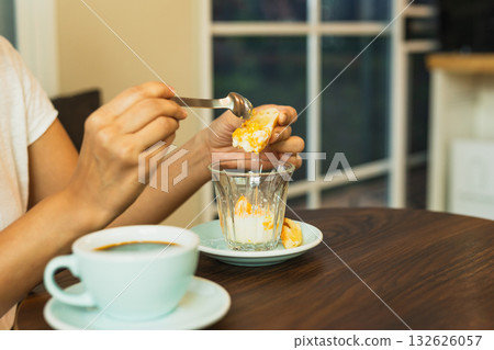 Woman eating soft boiled egg with slice of toast in cafe. 132626057