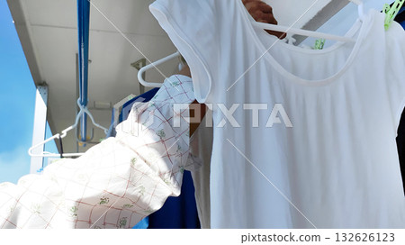 一位老人在陽台上曬衣物。 132626123