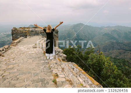 Happy woman on Simatai section of Great Wall of China in its original, un-restored state. Watchtowers perched on mountain peaks, China, Beijing. High quality photo Happy woman on Simatai section of Great Wall of China in its original, un-restored state. Watchtowers perched on mountain peaks, China, Beijing. High quality photo 132626456