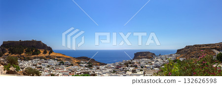 Panoramic view of colorful harbor in Lindos village and Acropolis, Rhodes. Aerial view of beautiful landscape, ancient ruins, sea with sailboats and coastline of island of Rhodes in Aegean Sea 132626598