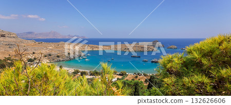 Panoramic view of colorful harbor in Lindos village and Acropolis, Rhodes. Aerial view of beautiful landscape, ancient ruins, sea with sailboats and coastline of island of Rhodes in Aegean Sea 132626606