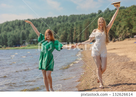 Smiling girls walking along coastline. Concept of friendship, entertainment and fun. High quality photo Smiling girls walking along coastline. Concept of friendship, entertainment and fun. High quality photo 132626614