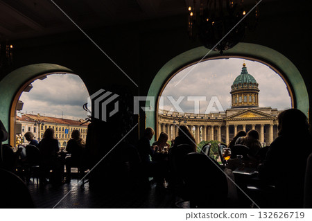 View of Kazan Cathedral from Singer Cafe through window. Silhouettes of people sitting at tables in old Singer House in Saint-Petersburg, Russia. High quality photo 132626719