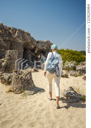 Two women exploring rock formations and caves in Pobiti Kamani natural reserve in Bulgaria on a sunny summer day. 132626964