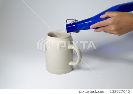 Pouring beer from a blue bottle into a mug 132627040