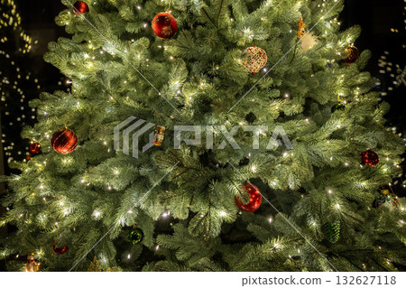 Close-up of a Christmas tree decorated with glowing lights and colorful ornaments, capturing the sparkle and warmth of the festive holiday season. Close-up of a Christmas tree decorated with glowing lights and colorful ornaments, capturing the sparkle and warmth of the festive holiday season. 132627118
