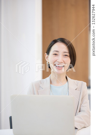 一位女商人坐在綠意盎然的窗邊,用電腦工作,目光看向鏡頭。 一位女商人坐在綠意盎然的窗邊,用電腦工作,目光看向鏡頭。 132627944