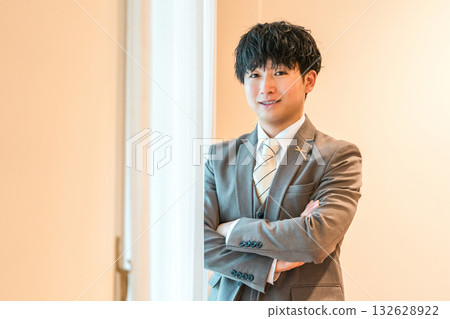 身穿西裝或燕尾服的新郎在婚禮場地的新娘房裡做準備 132628922