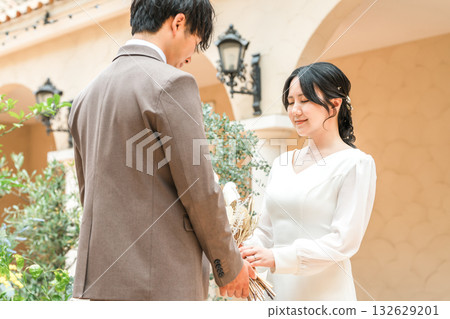 新郎新娘手捧花束，面對面站著（婚禮，新娘，情侶） 132629201