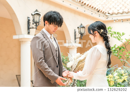 新郎新娘手捧花束，面對面站著（婚禮，新娘，情侶） 132629202