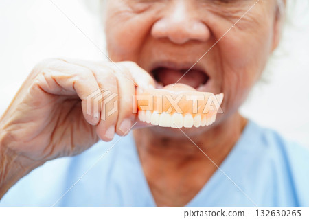 Asian senior woman patient holding teeth denture in her hand for chew food. 132630265