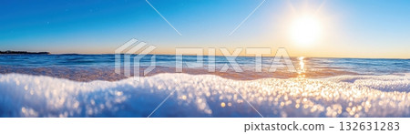 Breathtaking panoramic view of a tranquil sunset over a calm serene ocean beach with glowing horizon and reflective waves lapping the golden sandy shore  Peaceful 132631283