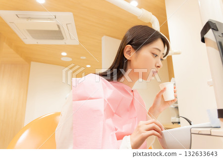 A woman rinsing her mouth after dental surgery 132633643