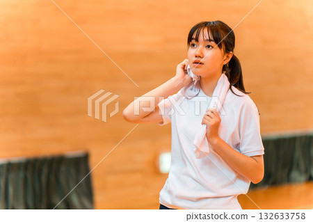 小學、國中、高中女生穿著運動服在體育館用毛巾擦汗 132633758
