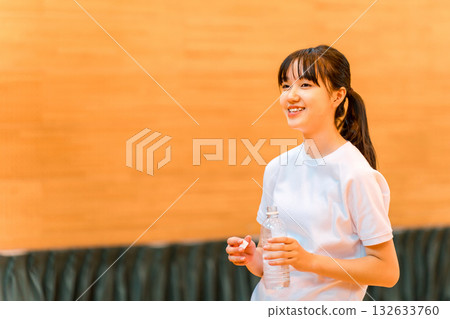 小學、國中和高中的女生穿著運動服在體育館喝瓶裝水補充水分 小學、國中和高中的女生穿著運動服在體育館喝瓶裝水補充水分 132633760