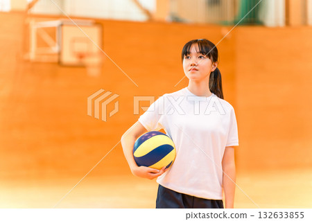 Junior high school and high school girls in gym clothes playing volleyball in a gym 132633855