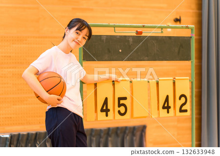 一名身穿運動服的女學生在體育館翻動記分牌 132633948