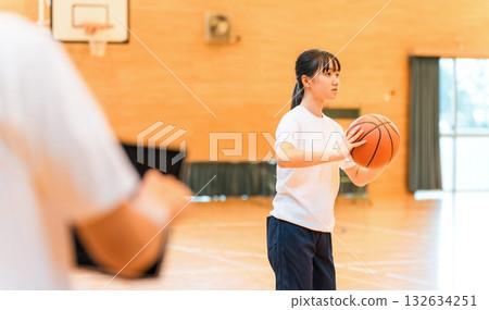 體育館裡,身著運動服、手拿籃球的女國中生和女高中生,以及一名男老師 體育館裡,身著運動服、手拿籃球的女國中生和女高中生,以及一名男老師 132634251