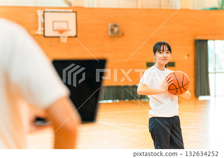 體育館裡，身著運動服、手拿籃球的女國中生和女高中生，以及一名男老師 132634252