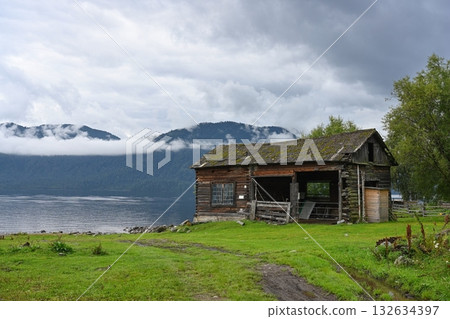 Abandoned wooden barn on the shore of a picturesque mountain lake 132634397