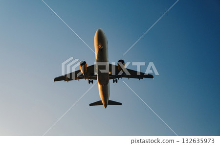 The image shows an airplane captured from a ground perspective, looking up towards the sky. The aircraft appears to be in mid-flight, with the landing gear extended, suggesting it is either about to The image shows an airplane captured from a ground perspective, looking up towards the sky. The aircraft appears to be in mid-flight, with the landing gear extended, suggesting it is either about to 132635973