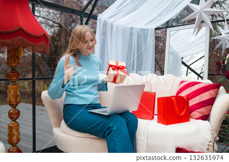 Smiling blonde woman waving during online Christmas video call Smiling blonde woman waving during online Christmas video call 132635974