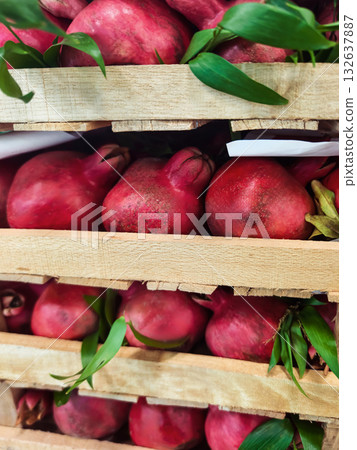 Fresh pomegranates stacked on wooden crates in a vibrant market setting Fresh pomegranates stacked on wooden crates in a vibrant market setting 132637887