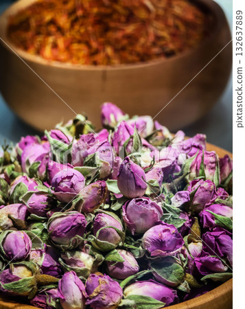Dried purple rosebuds and saffron displayed in traditional wooden bowls at a local market in the afternoon light 132637889