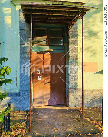 Old green residential entrance with a brown metal door under a simple corrugated canopy. The photo conveys an atmosphere of neglect and urban realism, suitable for illustrating topics about security Old green residential entrance with a brown metal door under a simple corrugated canopy. The photo conveys an atmosphere of neglect and urban realism, suitable for illustrating topics about security 132639002