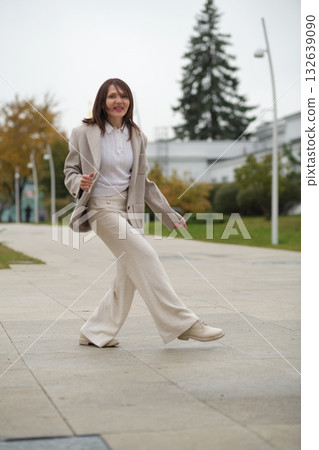 A mature woman gleefully spins on a sidewalk, enjoying the moment in her stylish outfit. The image encourages embracing life fully, regardless of age or societal expectations. A mature woman gleefully spins on a sidewalk, enjoying the moment in her stylish outfit. The image encourages embracing life fully, regardless of age or societal expectations. 132639090