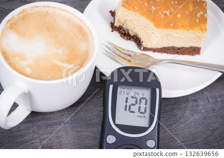 Glucose meter with high result sugar level, portion of sweet cheesecake and cup of coffee with milk 132639656