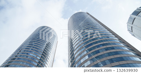 Sleek glass skyscrapers rise into a blue sky, showcasing modern architecture 132639930