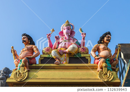 Vibrant scene featuring a pink Ganesha deity statue with two muscular guards Vibrant scene featuring a pink Ganesha deity statue with two muscular guards 132639943