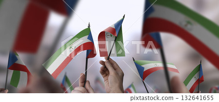 Equatorial Guinea flags in their hands on a blurred urban background 132641655