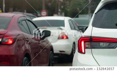 Rear side of white car with turn on brake light. Traffic jam on the road after rainy time. on the body of car with drop of water rain. Blurred traffic jam in the city with trees. 132641657