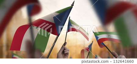 Equatorial Guinea flags in their hands on a blurred urban background Equatorial Guinea flags in their hands on a blurred urban background 132641660