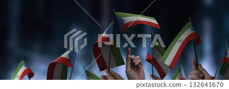 Equatorial Guinea flags in their hands on a blurred urban background Equatorial Guinea flags in their hands on a blurred urban background 132641670