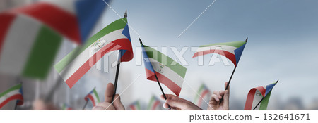 Equatorial Guinea flags in their hands on a blurred urban background 132641671