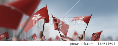 Hong Kong flags in their hands on a blurred urban background 132641691